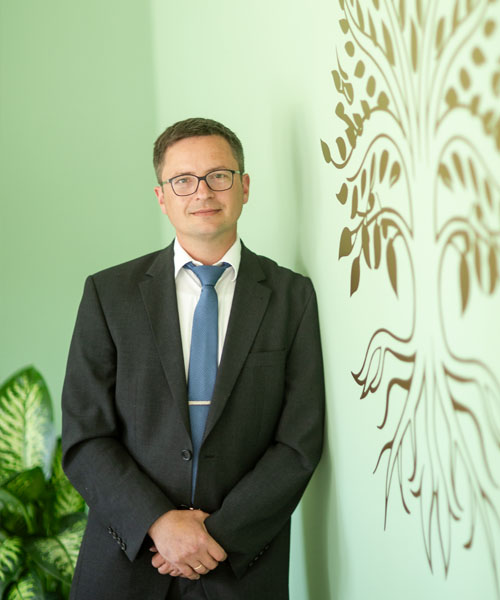 Jens Kallwaß vor dem Baum-des-Lebens-Symbol im Beratungsraum